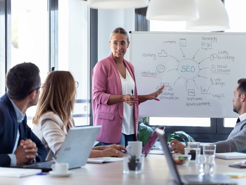 young-businesswoman-pointing-at-white-blackboard-a-NU2N2WV.jpg